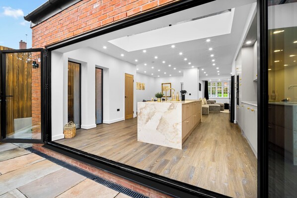 A modern kitchen with a central island, white walls, and a wooden floor.