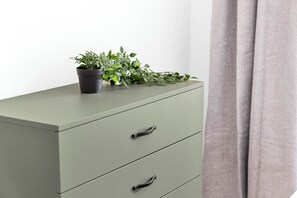 A light green filing cabinet with two drawers and a potted plant on top.