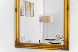Ein Essbereich mit Tisch für zwei Personen, einer Lampe und gerahmten Kunstwerken an der Wand.