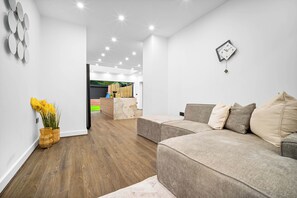 Ein modernes Wohnzimmer mit einer Couch, einer Uhr und einem dekorativen Spiegel an der Wand.