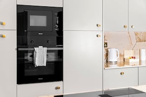 Eine Küche mit einem Hisense-Ofen und einer Mikrowelle, ein Handtuch hängt an der Ofentür und eine Kaffeemaschine steht auf der Arbeitsplatte.