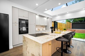 A modern kitchen with a built-in oven, a large island with bar stools, and a view of the outdoors.