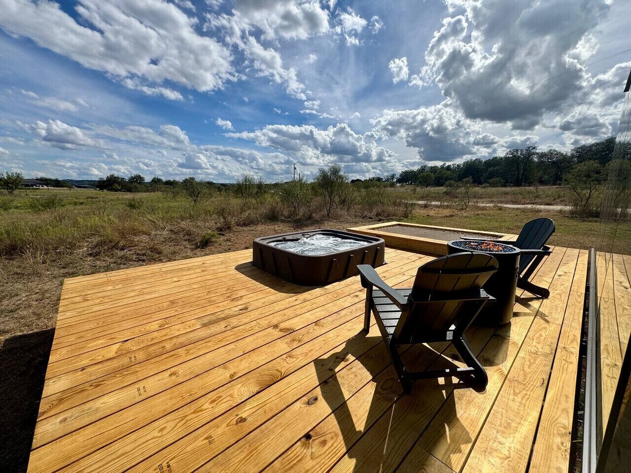 En træterrasse med et spabad og to Adirondack-stole.