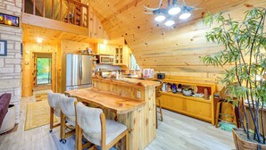 Una cabaña de madera con cocina, comedor y habitación en el altillo.