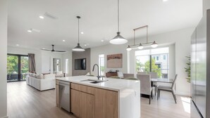 Une cuisine moderne dotée d’un îlot central, d’un coin repas et d’un espace détente avec un canapé et des fauteuils.