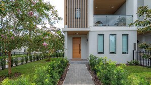 Un bâtiment moderne à deux étages, doté d’une entrée centrale, d’une porte en bois et d’un chemin pavé menant à l’entrée.