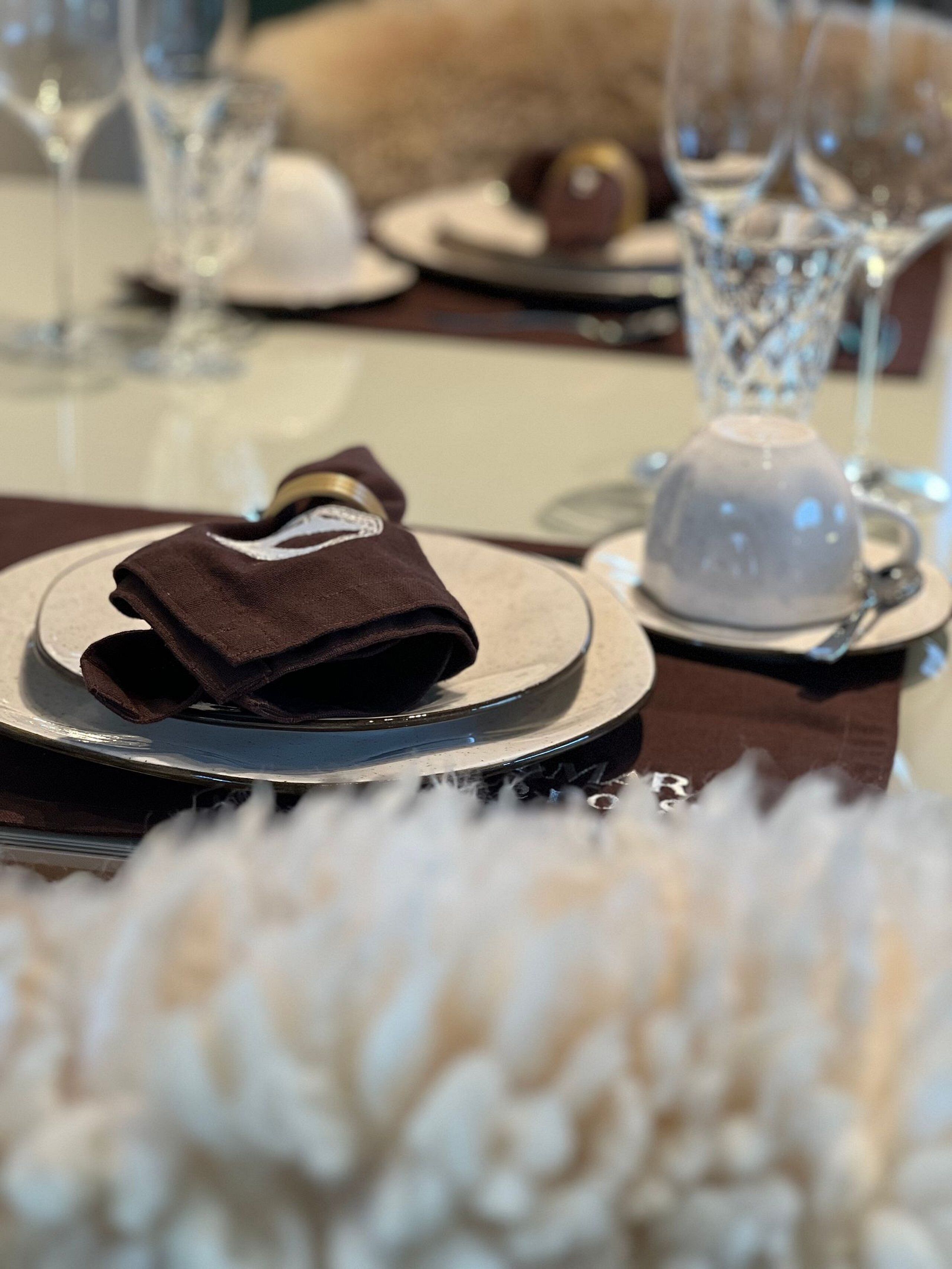 A table set with a folded napkin, a teapot, and a cup on a saucer.