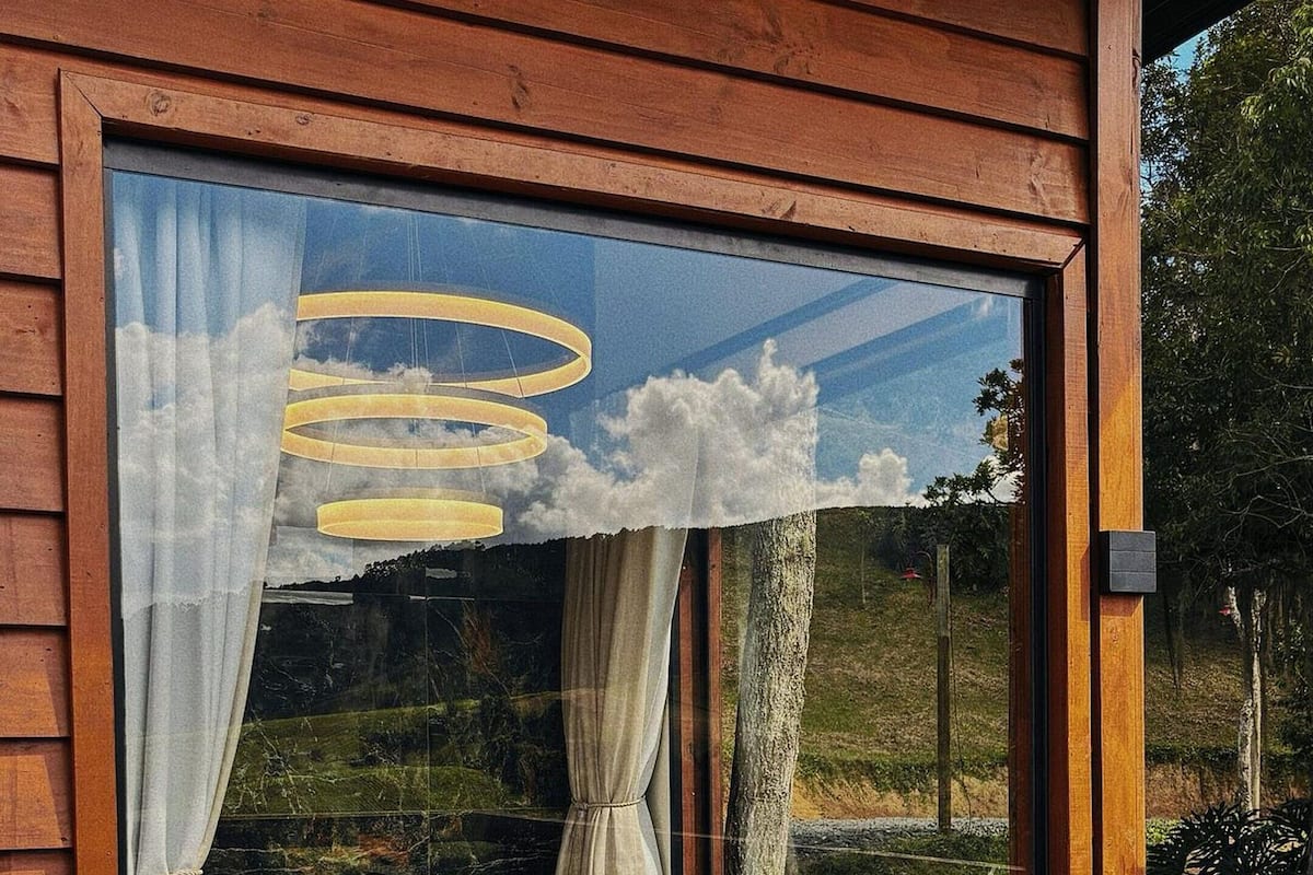 A wooden cabin with a large window revealing a modern bathroom with a bathtub, a shower, and a sink.