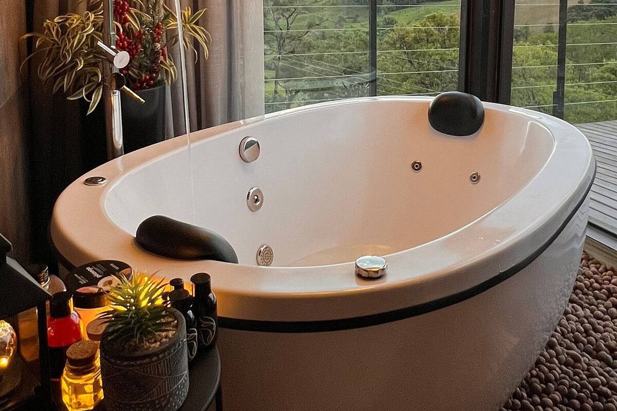 A modern bathroom with a freestanding bathtub, large windows, and a view of the countryside.