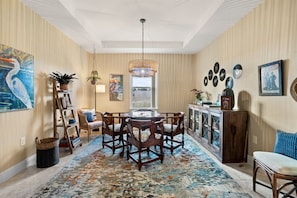 A dining area with a round table, chairs, a chandelier, and a patterned rug. - 4BR Sebastian Getaway • Beaches, Surf & Fishing (Sebastian)