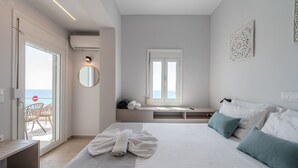 Hotellihuone, jossa on sänky, penkki, näköalalla varustettu ikkuna ja parveke, jossa on tuoleja.
