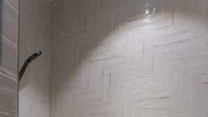 A shower with a herringbone tile pattern and a visible showerhead. - Comfortable Apartment - 1br/2p - Le Marais (Paris)