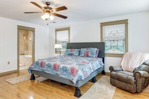 A bedroom with a bed, a chair, a ceiling fan, and a window with blinds.
