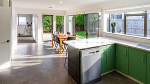 Una cucina moderna con mobili verdi, una lavastoviglie e un'area pranzo con tavolo e sedie.