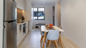 Eine moderne Küche mit integriertem Kühlschrank, einem Esstisch mit Stühlen und einem Fenster, das für natürliches Licht sorgt.