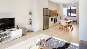 Eine moderne Wohnung mit Wohnzimmer, Essbereich, Küchenzeile und Fernseher.