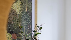 A dining table with a vase of flowers, two chairs, and a window with a painting. - Urban Utopia 2 Bedroom Retreat (Christchurch)