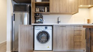 Una cocina compacta con lavadora integrada, un refrigerador y una cafetera.