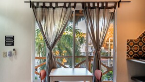 A room with a table and chairs, a window with curtains, a wall-mounted thermostat, and a patterned wall.