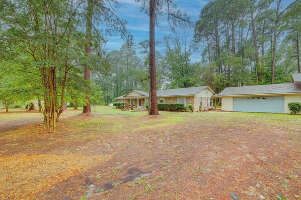 A residential area with multiple houses, a grassy yard, and a large tree. - Family Getaway on 4 Acres in Mineola! (Mineola)
