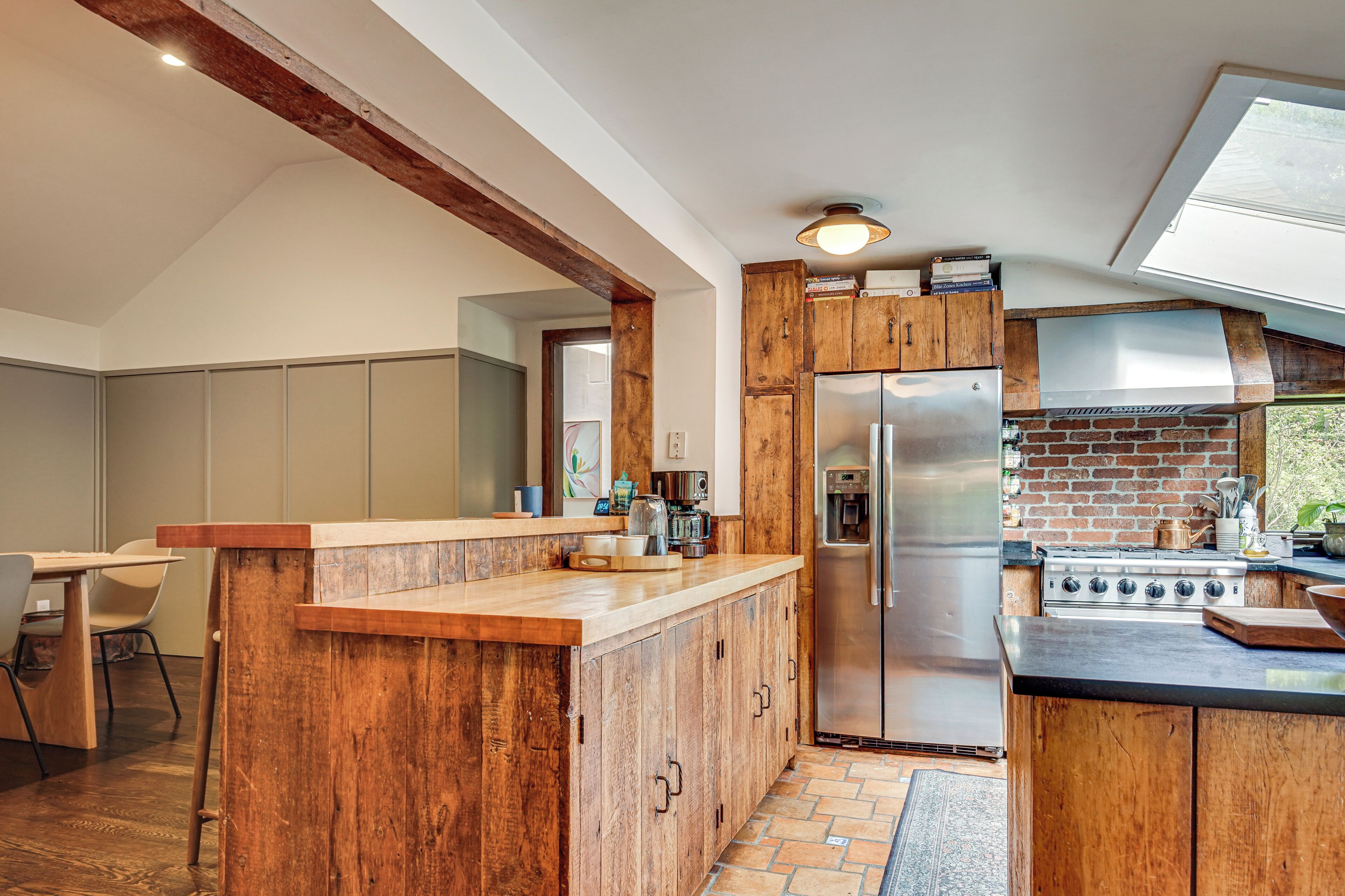 Una cocina moderna con armarios de madera, un refrigerador de acero inoxidable y un horno de ladrillo.