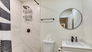 A bathroom with a toilet, a sink, a mirror, and a shower area. - Fenced-In Yard: Home < 5 Mi to Dtwn Dallas! (Dallas)