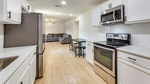 A modern kitchen with white cabinets, stainless steel appliances, and a wooden floor. - Fenced-In Yard: Home < 5 Mi to Dtwn Dallas! (Dallas)