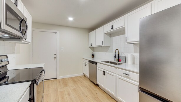 A modern kitchen with white cabinets, stainless steel appliances, and a wooden floor. - Fenced-In Yard: Home < 5 Mi to Dtwn Dallas! (Dallas)