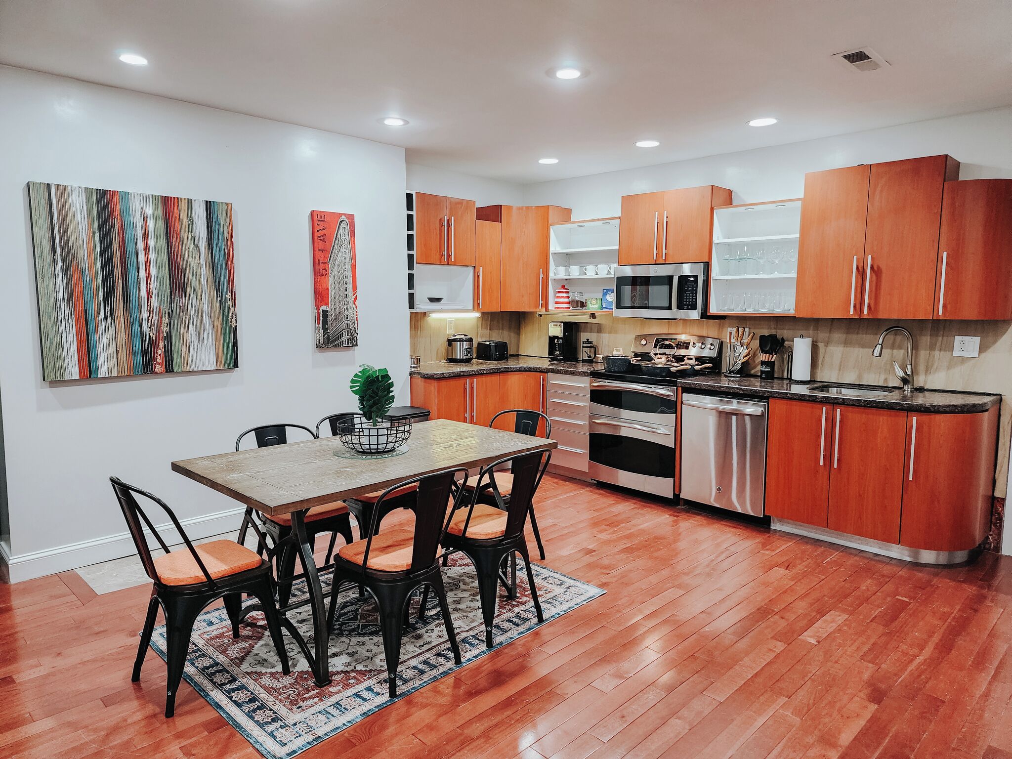 A modern kitchen with wooden cabinets, stainless steel appliances, and a dining area with a table and chairs.