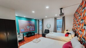 Habitación de hotel con dos camas, televisor, escritorio y armario.