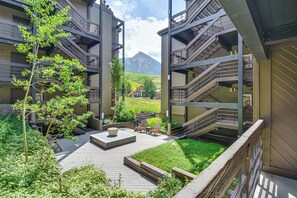 Een modern gebouw met meerdere balkons en een centrale binnentuin met zitplaatsen en beplanting.