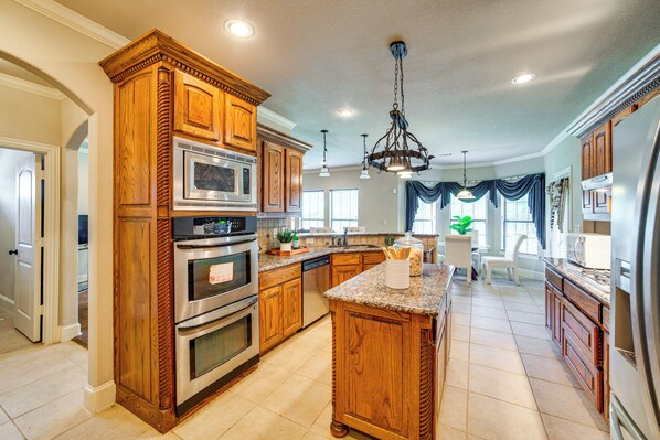 A spacious kitchen with wooden cabinetry, stainless steel appliances, and a central island.