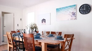 Comedor con una mesa de madera dispuesta para seis personas, rodeada de sillas de madera.