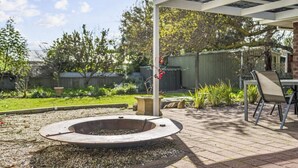 Un patio cubierto con una chimenea, muebles de exterior y un sendero de ladrillo.