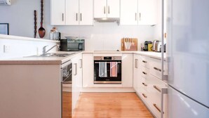 Una cocina moderna con armarios blancos, horno empotrado, microondas y refrigerador.