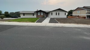 A residential area with houses, a driveway, and a grassy lawn. - Spacious 3-bedroom Lakeview Home Centrally Located in Quiet Neighborhood (Moses Lake)