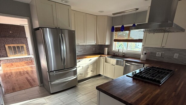 A modern kitchen with a stainless steel refrigerator, wooden countertop, and light-colored cabinets. - Spacious 3-bedroom Lakeview Home Centrally Located in Quiet Neighborhood (Moses Lake)