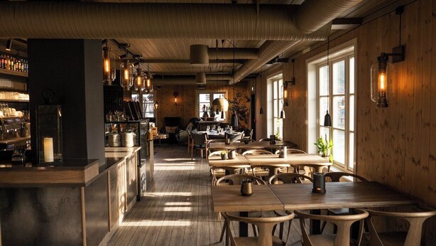 Un ristorante con interni in legno, tavoli, sedie e lampadari.