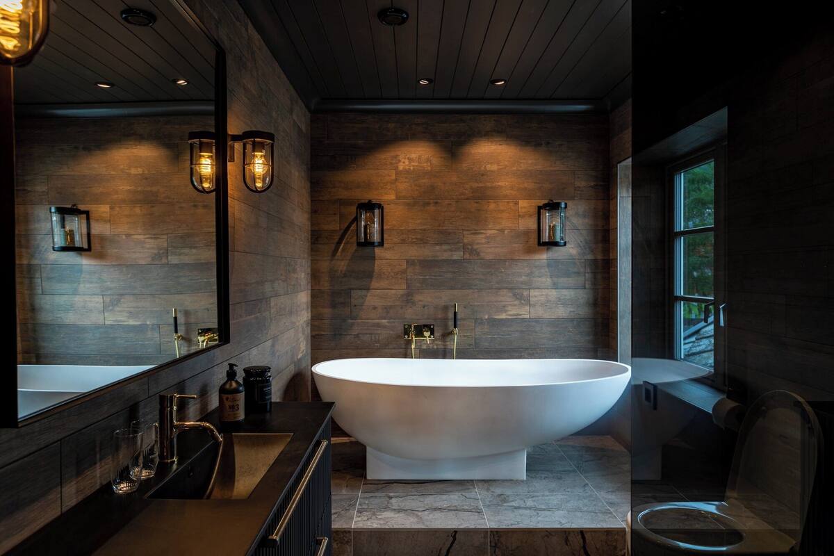 Une salle de bain moderne avec une baignoire sur pieds, des murs en bois et des luminaires encastrés.
