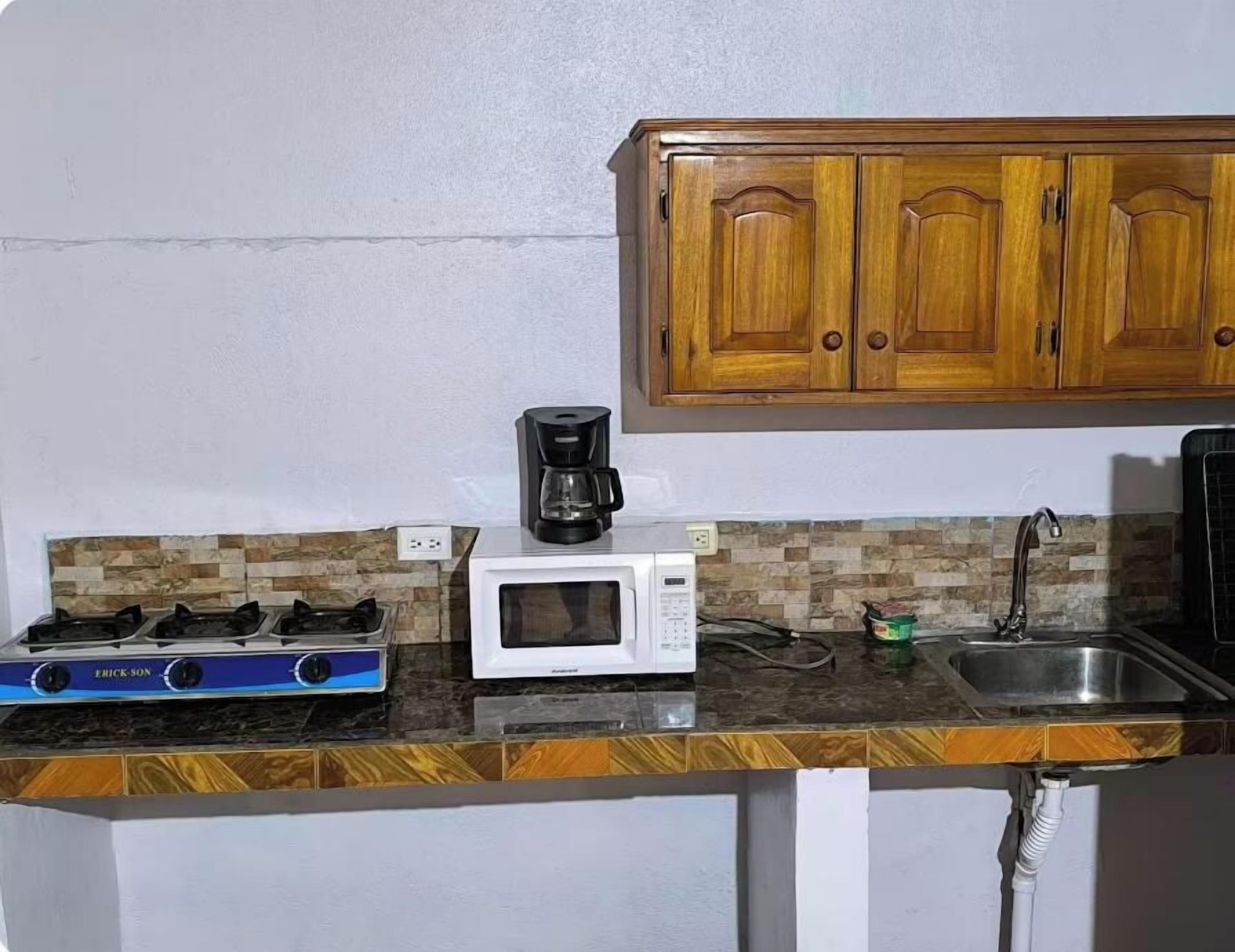 A kitchen with a gas stove, microwave, coffee maker, and wooden cabinets.