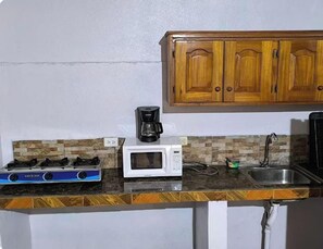A kitchen with a gas stove, microwave, coffee maker, and wooden cabinets.
