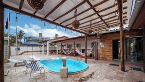 An outdoor swimming pool with lounge chairs and a hammock. - Casa c 5 su tes Piscina Churrasqueira e Sinuca (Cabedelo)