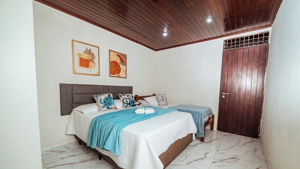 A bedroom with two beds, a wooden ceiling, and a tiled floor. - Casa c 5 su tes Piscina Churrasqueira e Sinuca (Cabedelo)