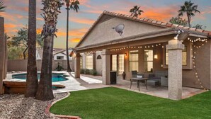A covered patio area with outdoor seating, a swimming pool, and a well-maintained lawn. - 3BR Spacious Scottsdale Home w/ Hot Tub & Pool! (Scottsdale)