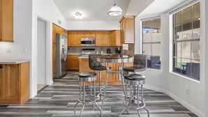 A modern kitchen with wooden cabinets, stainless steel appliances, and a bar area with stools. - 3BR Spacious Scottsdale Home w/ Hot Tub & Pool! (Scottsdale)