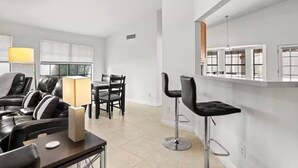 A modern living room with a sofa, a dining table, and two bar stools. - 3BR Spacious Scottsdale Home w/ Hot Tub & Pool! (Scottsdale)