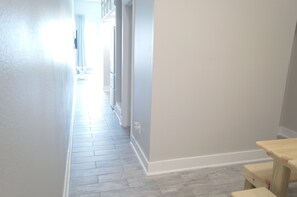 Un couloir doté d’un plancher en bois, de murs blancs et d’une petite table en bois.