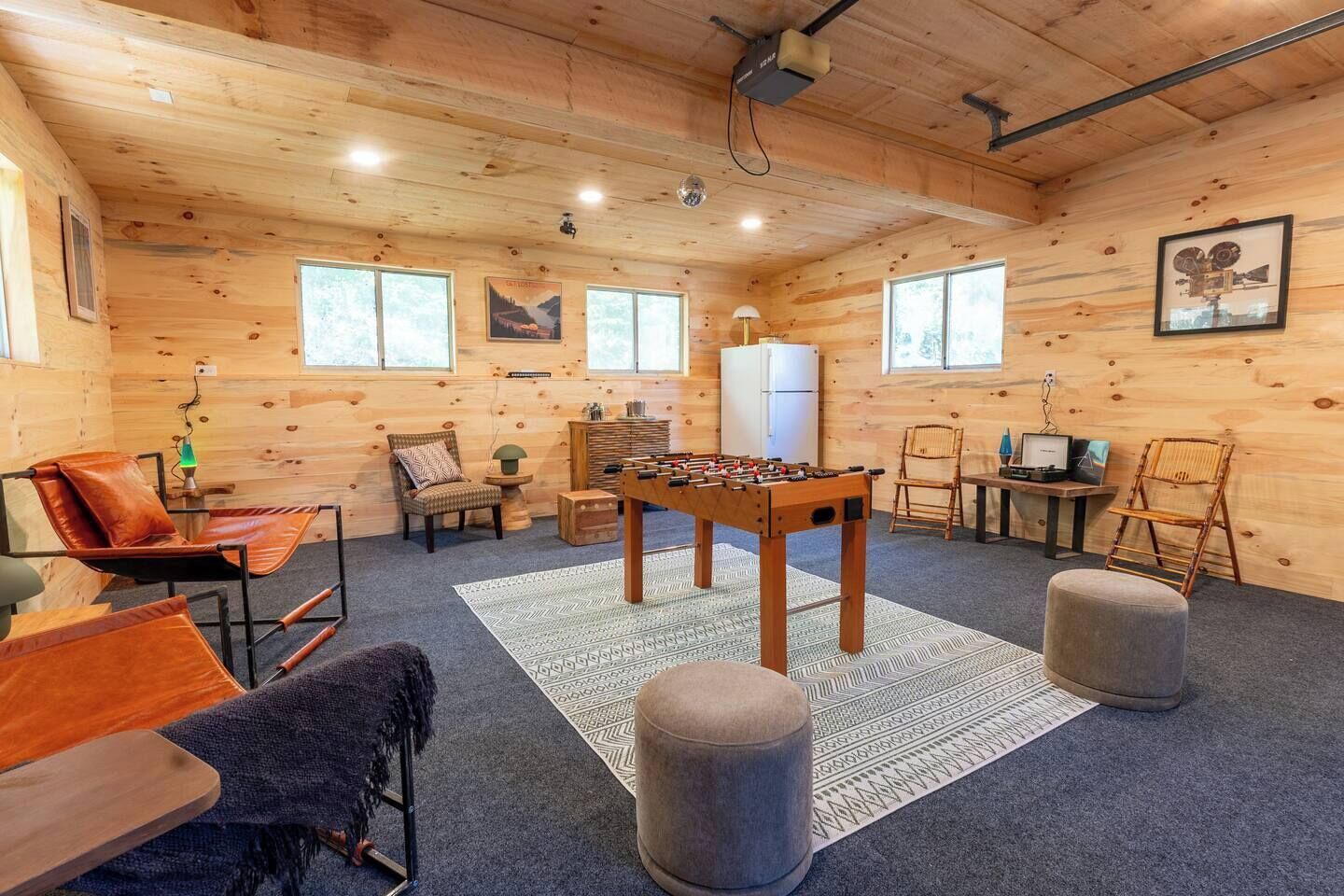 Une pièce confortable avec un baby-foot, un canapé, un fauteuil et une petite table avec une lampe.