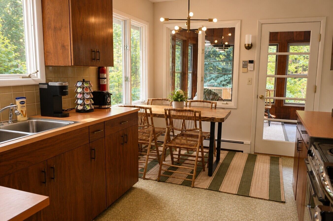 A kitchen with wooden cabinets, a coffee maker, a toaster, and a dining area with a table and chairs.