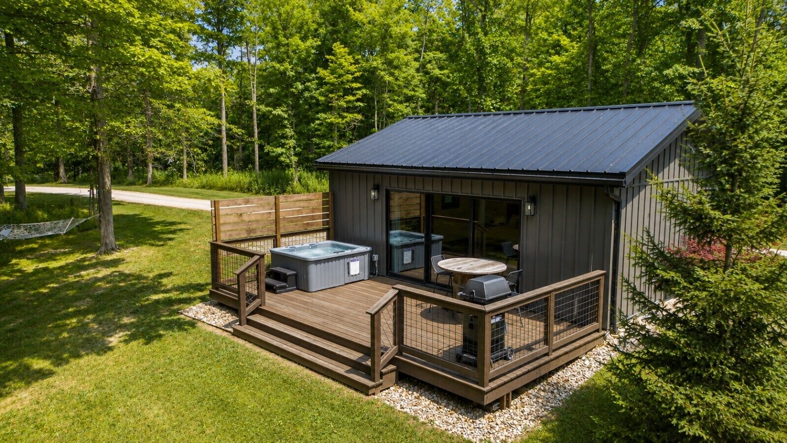 A wooden cabin with a deck, a hot tub, and a barbecue area.